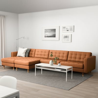 Modern living room: tan leather section sofa, white coffee table, grey rug, wall art.