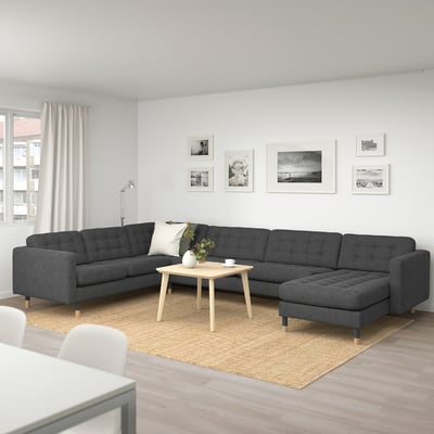 Large grey l-shaped LANDSKRONA sofa, wood coffee table, rug, white curtain, wall decorations in modern living room.