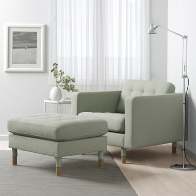 Modern living room with light green LANDSKRONA armchair & footstool, white side table, grey rug, and floor lamp.