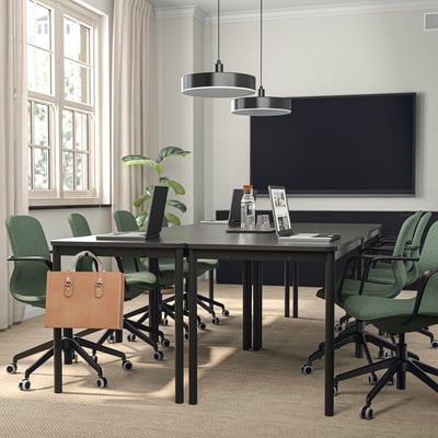 Modern office with green chairs, laptop, black lights, and tv.