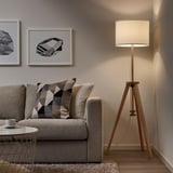 Modern living room with LAUTERS floor lamp, recycled shade, beside grey sofa, warm light, geometric wall art.