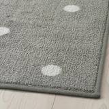 Gray rectangular rug with white dots, laid on a wooden floor, featuring a durable, textured surface and secure rubber backing.