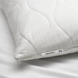 Close-up of a white ergonomic pillow with intricate stitching, featuring a tag that reads LÖKSTAMFLY by ikea.