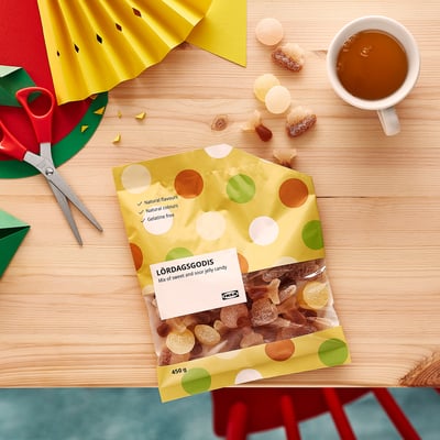 LÖRDAGSGODIS candy bag with shapes, scattered candies, and coffee.