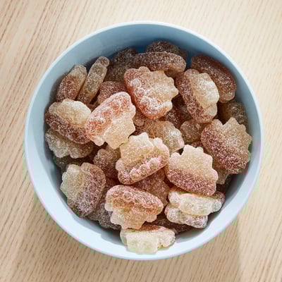 Bowl of light blue with assorted sugar-coated candies, white and brown.