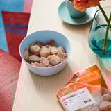 Bowl of colorful candies on wooden table, next to orange packaging labeled LÖRDAGSGODIS.