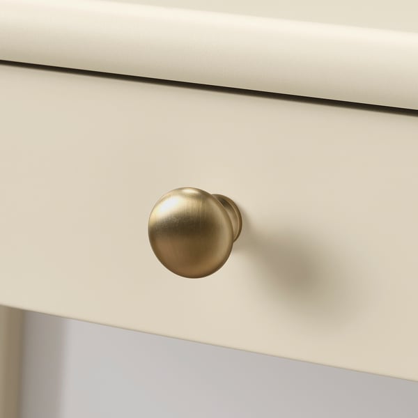 Gold-colored round doorknob on a white drawer, highly polished, showing excellent craftsmanship and quality.