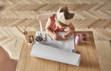 Child drawing with MÅLA paper at wooden table.