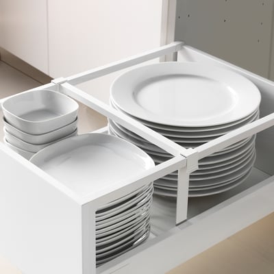Organized kitchen drawer with stacked plates, bowls, and lids for easy access. Drawers extend fully for visibility.