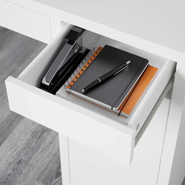 Open white desk drawer with notebook, pen, and binder showing cable management and adjustable shelves.