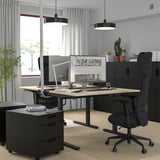 Modern home office: MITTZON adjustable desk, dark, light wood top, black chair, pendant lamps, filing cabinet, plants.