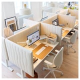 Modern office space with MITTZON white desks, ergonomic chairs, and computer monitors. Neatly organized with accessories and decorations.