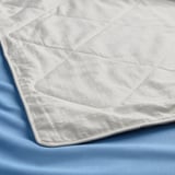 Close-up of a luxurious, textured silk duvet on a blue sheet, showcasing its soft, high-quality material.