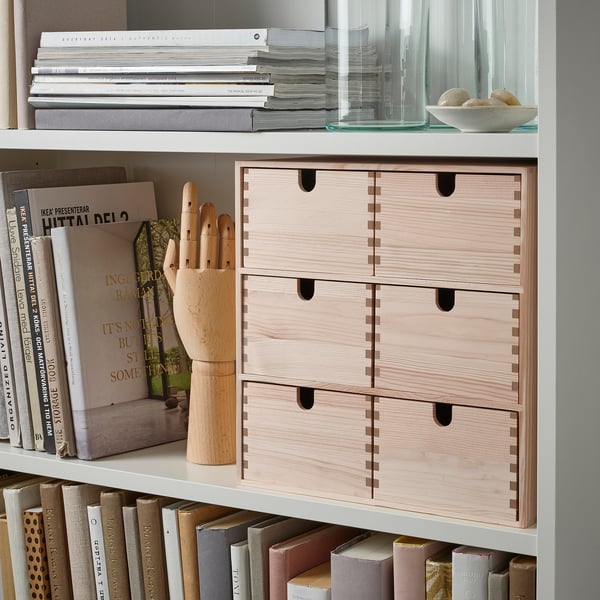 White bookshelf with light wood drawers, books, and decorative items.