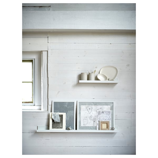 Minimalist white wall shelves hold decorative vases and framed art.