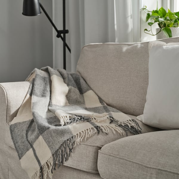 MYRULL throw blanket in light grey on couch, covers cushions, fringed ends.