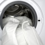 Washing thick, padded mattress topper inside white dryer.