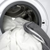 White washing machine drum with gray NOPAKTE mattress pad for comfort.