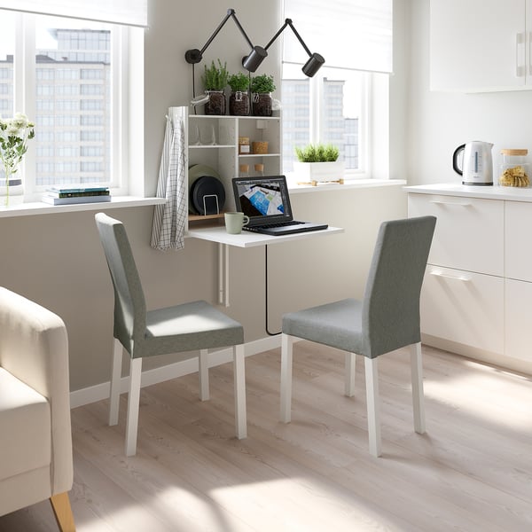 Modern minimalist workspace: white wall-hung table with storage, two gray chairs, large window, city view.