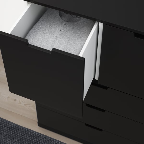 Black chest of drawers with one drawer open, revealing a gray sweater and a soft-close mechanism.