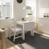 White NORDVIKEN drop-leaf table & chairs by window, on black/white rug, modern kitchen.