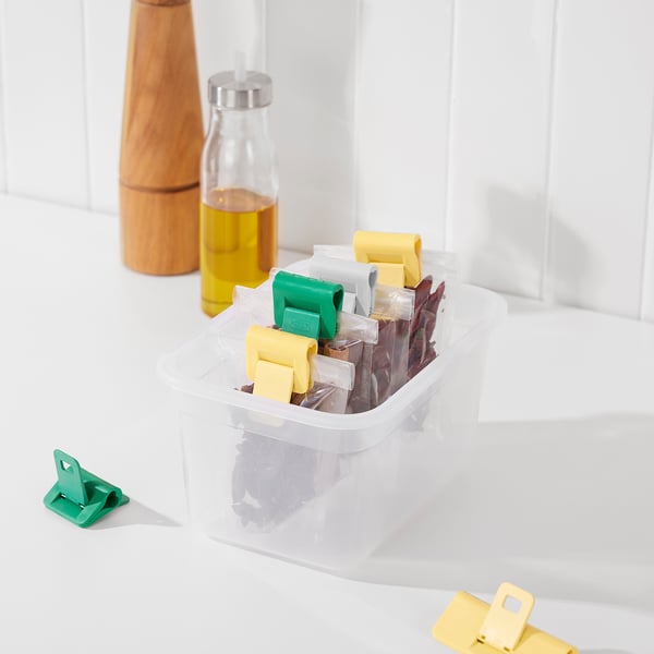 Transparent container with colorful sealing clips, pepper mill, and oil bottle.