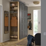 Modern PAX wardrobe with open and closed storage. Tall, dark grey, light wood top. Hangs coats, stores shoes, bags. Next to white door.