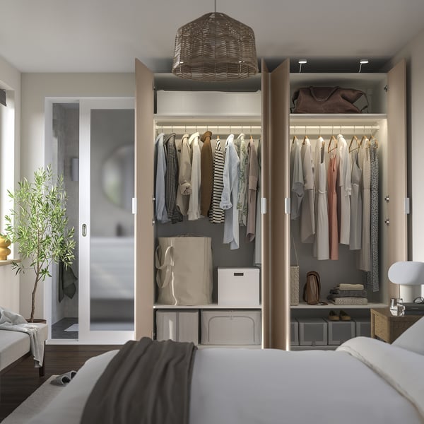 Modern closet with sliding doors, organized clothes and storage, highlighted by lighting.