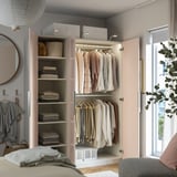 Organized closet with clothes, towels, baskets, and lighting.