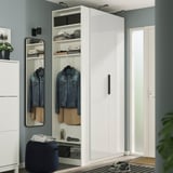 A tall, white PAX wardrobe with sleek finish, mirror, shelves, and hanging rails showcasing clothes and shoes, fitting perfectly by the door.
