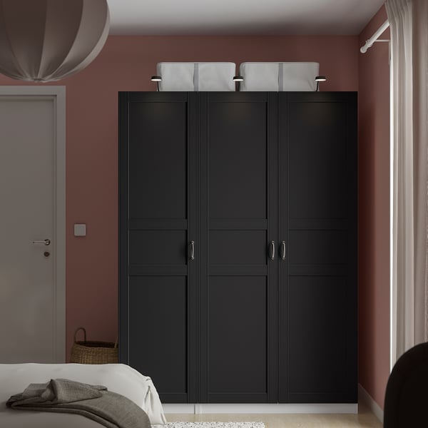 Black PAX wardrobe, closed, against red wall, with basket, dominates room.