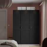 Black PAX wardrobe, closed, against red wall, with basket, dominates room.