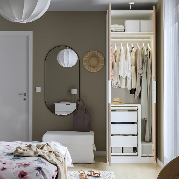 A minimalist bedroom with an open wardrobe displaying clothes, drawers, and an adjustable divider.