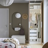 A minimalist bedroom with an open wardrobe displaying clothes, drawers, and an adjustable divider.