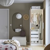 Small bedroom with open wardrobe showing clothes and drawers. Wardrobe has an adjustable divider for long garments.