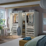 A modern bedroom with a PAX wardrobe featuring hanging clothes, drawers, and shelves. It has integrated lighting and adjustable interiors.