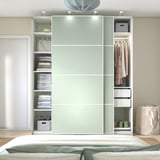 Modern bedroom with mint-green PAX wardrobe displaying clothes and storage.