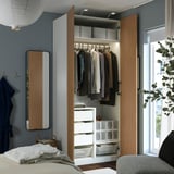 Open wooden wardrobe reveals clothes on hangers, drawers, and storage bins, with a mirror and coat hooks to the side.