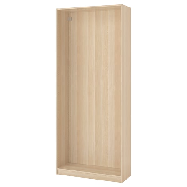 An ikea PAX wardrobe frame in light oak. Its tall, rectangular, and made of particleboard with a light wooden finish.
