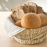 A woven basket holding bread, with a striped cloth inside.