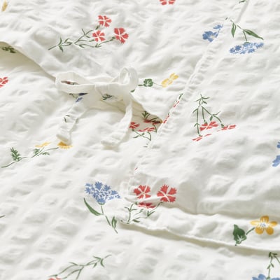 White duvet cover with colorful floral patterns, featuring a seersucker texture, tied at the corner.