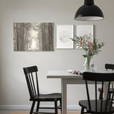 Modern dining area with black chairs, table, and pendant lamp. Wall has PJÄTTERYD picture, flowers, and newspaper.