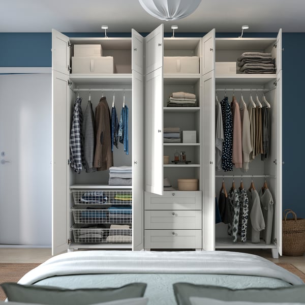 Open wardrobe with adjustable sections, clothes, shelves, and drawers. Wall-anchored with hinges and handles.