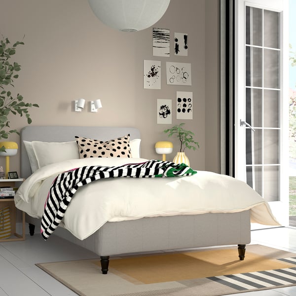 Modern bedroom with gray bed, white duvet, yellow lamps, and wall art.