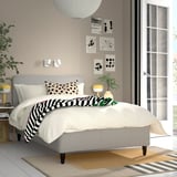 Modern bedroom with gray bed, white duvet, yellow lamps, and wall art.
