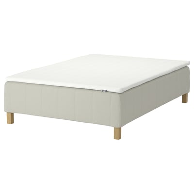 A white RÅHOLMAR mattress with five comfort zones, supported by wooden legs, offering a firm and relaxing sleep surface.
