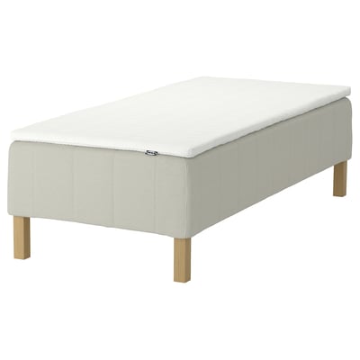 A white IKEA RÅHOLMAR mattress with a simple design and wooden legs.