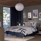 Modern bedroom with gray walls, large bed, pendant lamp, nightstand, and plant by window.