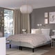 Modern bedroom with RÅHOLMAR bed, neutral linens, grey walls, pendant light, nightstands, and large window with beige curtains.
