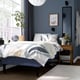 Modern blue bedroom: RÅHOLMAR bed, white linens, bedside table, plant, grey towels, large mirror.